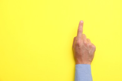 Photo of Man touching something on yellow background, top view. Space for text