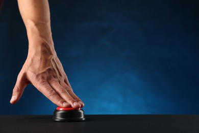 Photo of Man pressing button on black table against blue background, closeup. Space for text