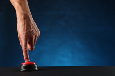 Photo of Man pressing button on black table against blue background, closeup. Space for text