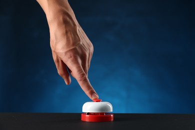 Photo of Man pressing button on black table against blue background, closeup. Space for text