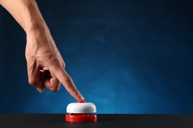 Photo of Man pressing button on black table against blue background, closeup. Space for text