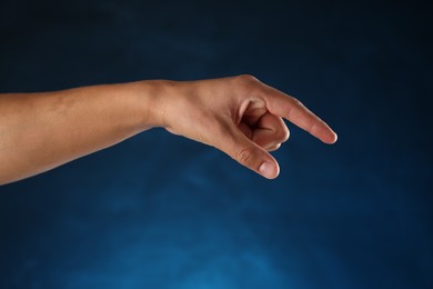 Photo of Man touching something on blue background, closeup