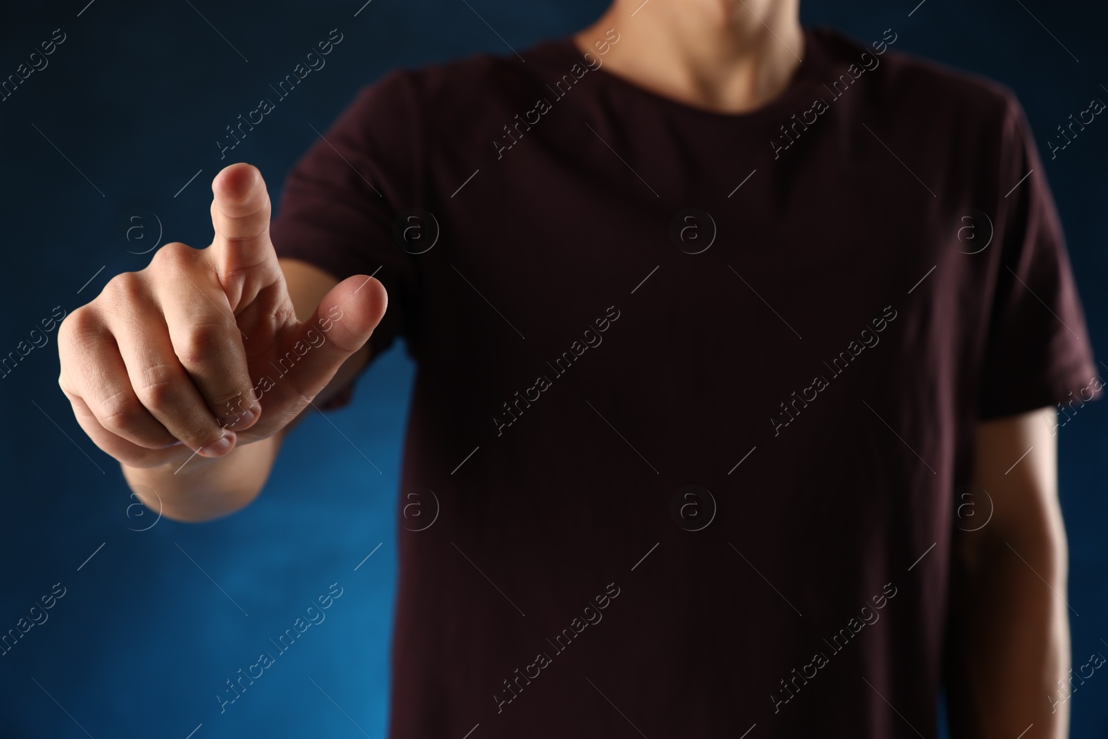 Man touching something on blue background, closeup Photo of Man touching something on blue background, closeup