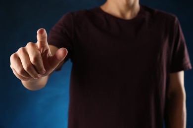 Photo of Man touching something on blue background, closeup