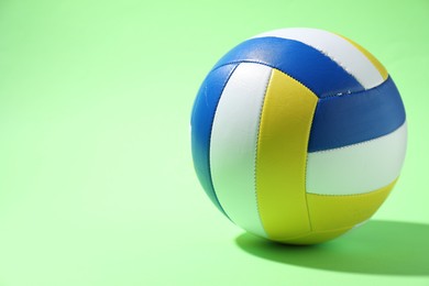 Photo of Colorful volleyball ball on light green background. Space for text
