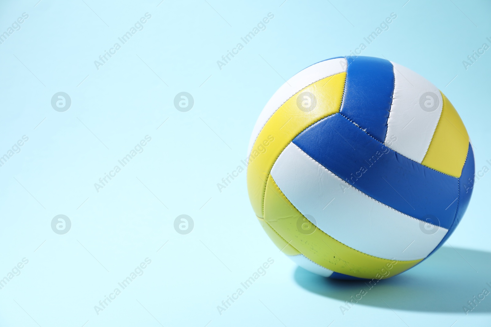 Photo of Colorful volleyball ball on light blue background. Space for text