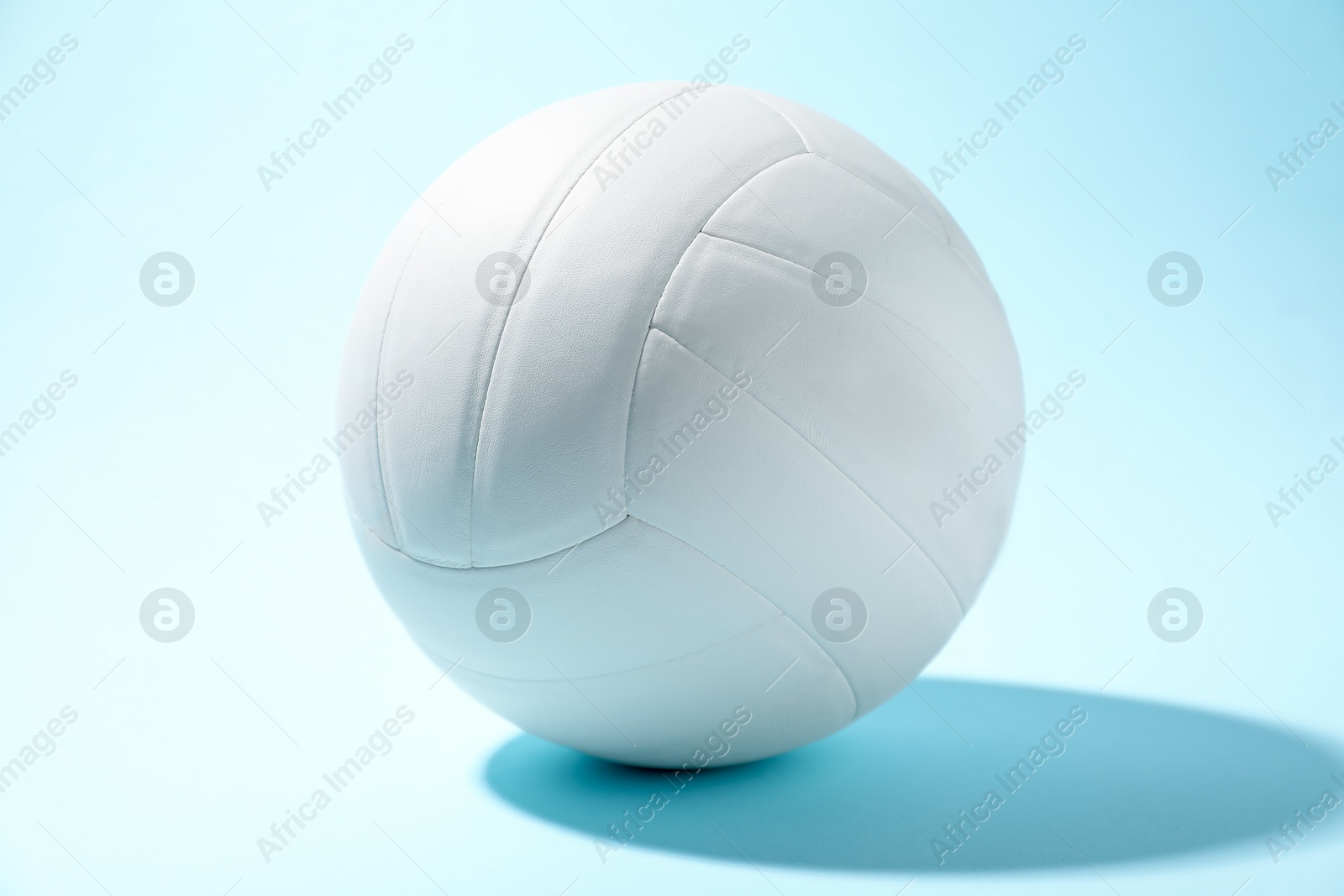 Photo of One white volleyball ball on light blue background