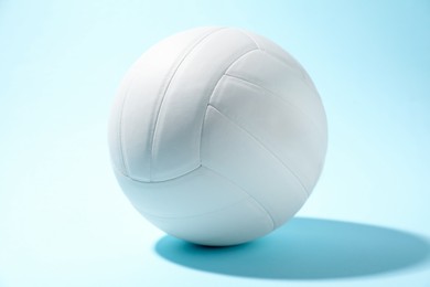 Photo of One white volleyball ball on light blue background