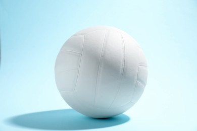 Photo of One white volleyball ball on light blue background
