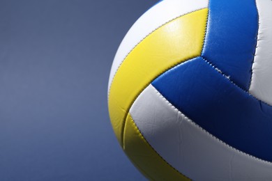 Photo of Colorful volleyball ball on blue background, closeup. Space for text