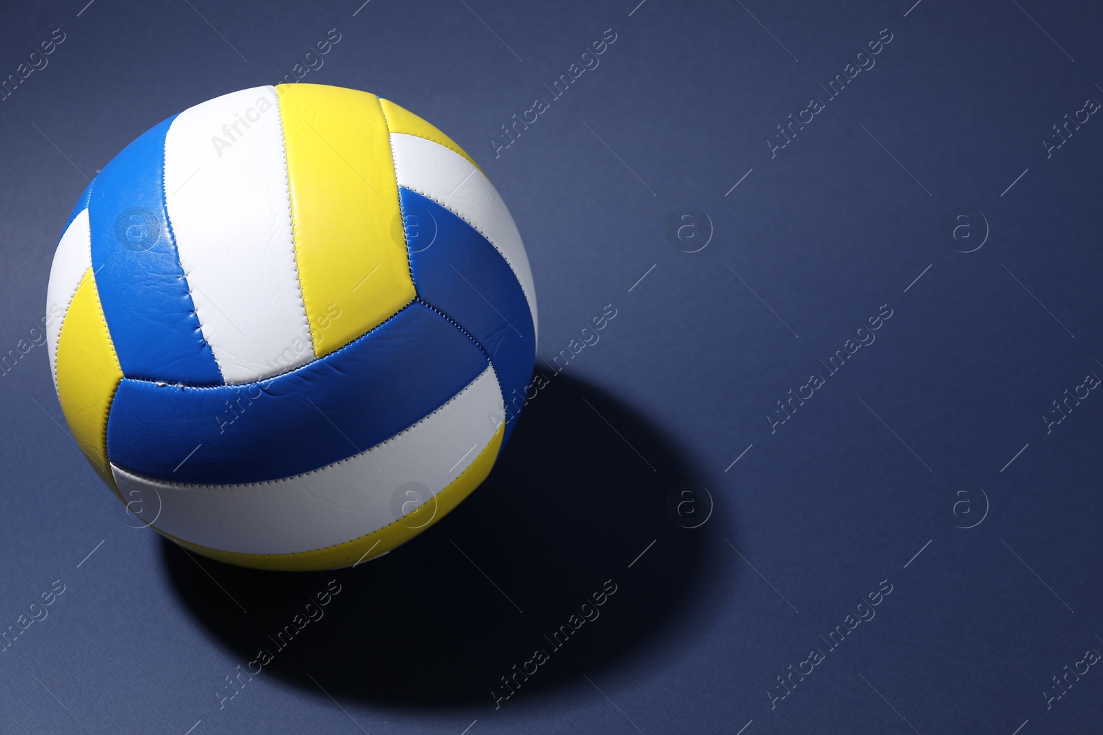 Photo of Colorful volleyball ball on blue background. Space for text