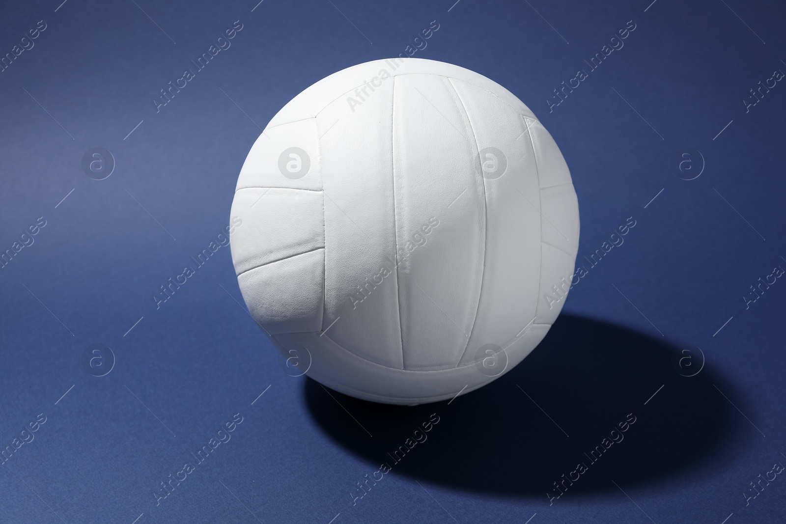 Photo of One white volleyball ball on blue background