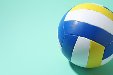 Photo of Colorful volleyball ball on turquoise background. Space for text