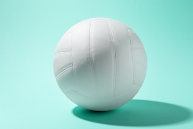 Photo of One white volleyball ball on turquoise background