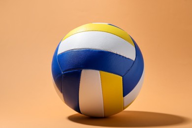 Photo of Colorful volleyball ball on pale orange background