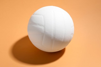 Photo of White volleyball ball on pale orange background