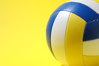 Photo of Colorful volleyball ball on yellow background, closeup. Space for text