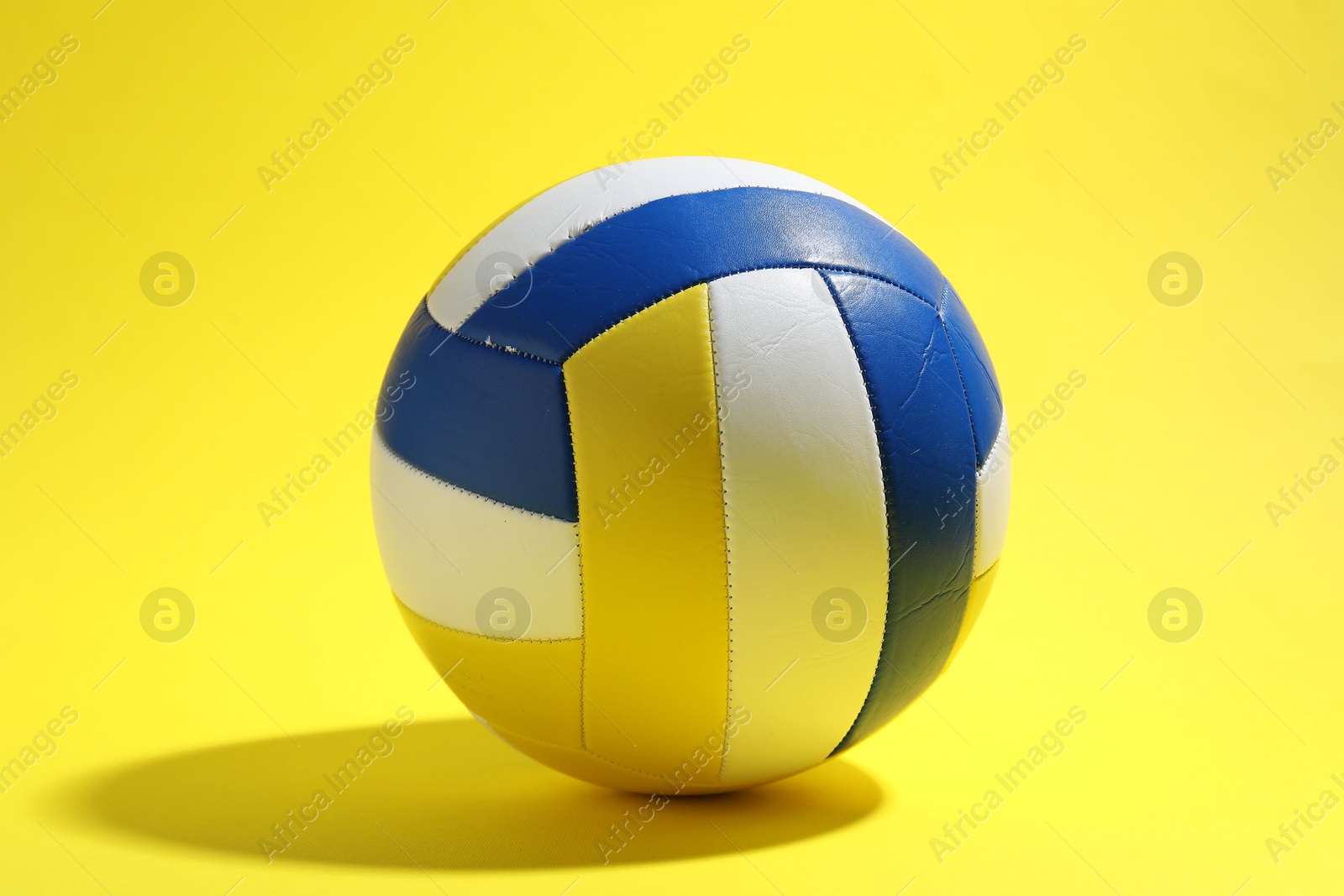 Photo of One colorful volleyball ball on yellow background