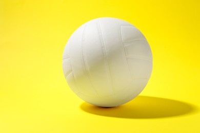 Photo of One white volleyball ball on yellow background