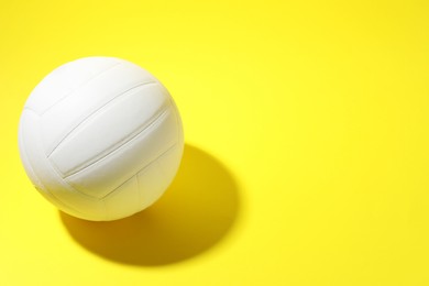 Photo of White volleyball ball on yellow background, above view. Space for text