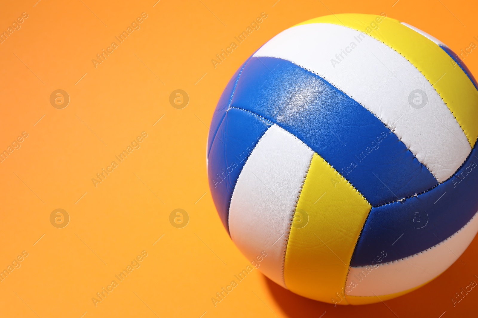 Photo of Colorful volleyball ball on orange background, closeup. Space for text
