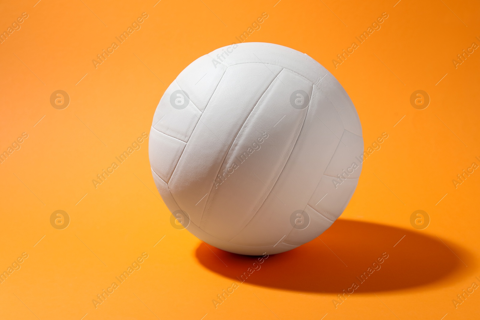 Photo of One white volleyball ball on orange background