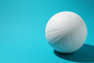 Photo of White volleyball ball on light blue background. Space for text