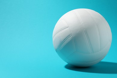Photo of White volleyball ball on light blue background. Space for text