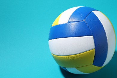 Photo of Colorful volleyball ball on light blue background, closeup. Space for text