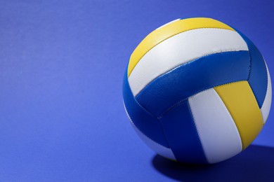Photo of Colorful volleyball ball on blue background, closeup. Space for text
