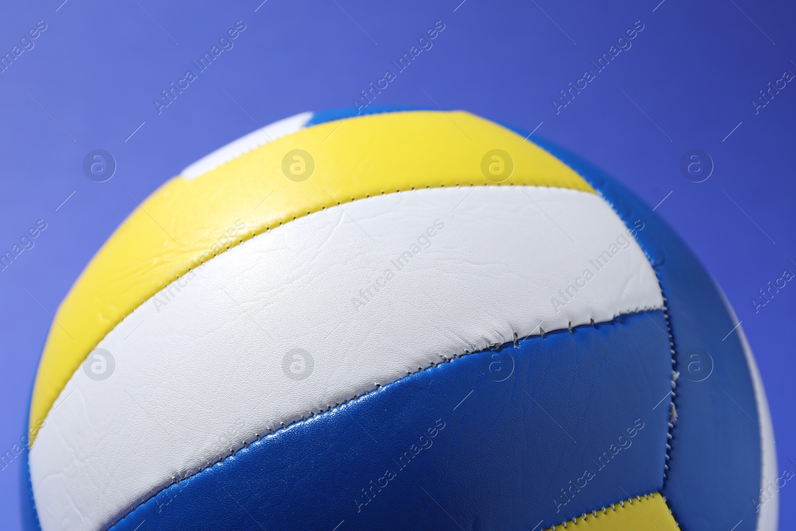 Photo of Colorful volleyball ball on blue background, closeup