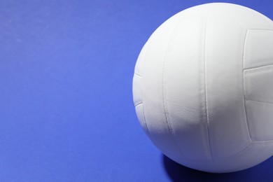 Photo of White volleyball ball on blue background, closeup. Space for text