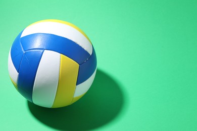 Photo of Colorful volleyball ball on green background. Space for text