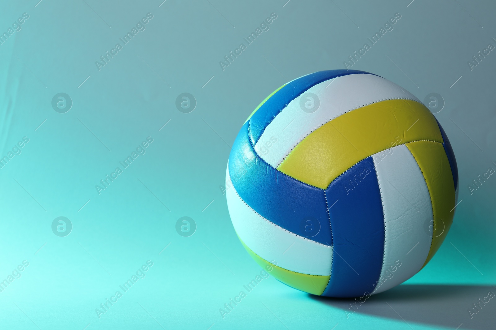 Photo of Colorful volleyball ball on light blue background. Space for text