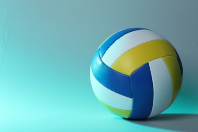 Photo of Colorful volleyball ball on light blue background. Space for text