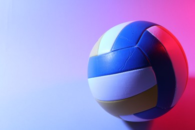 Photo of Colorful volleyball ball on light background in color lights. Space for text