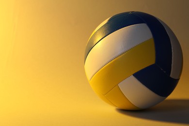 Photo of Colorful volleyball ball on yellow background. Space for text