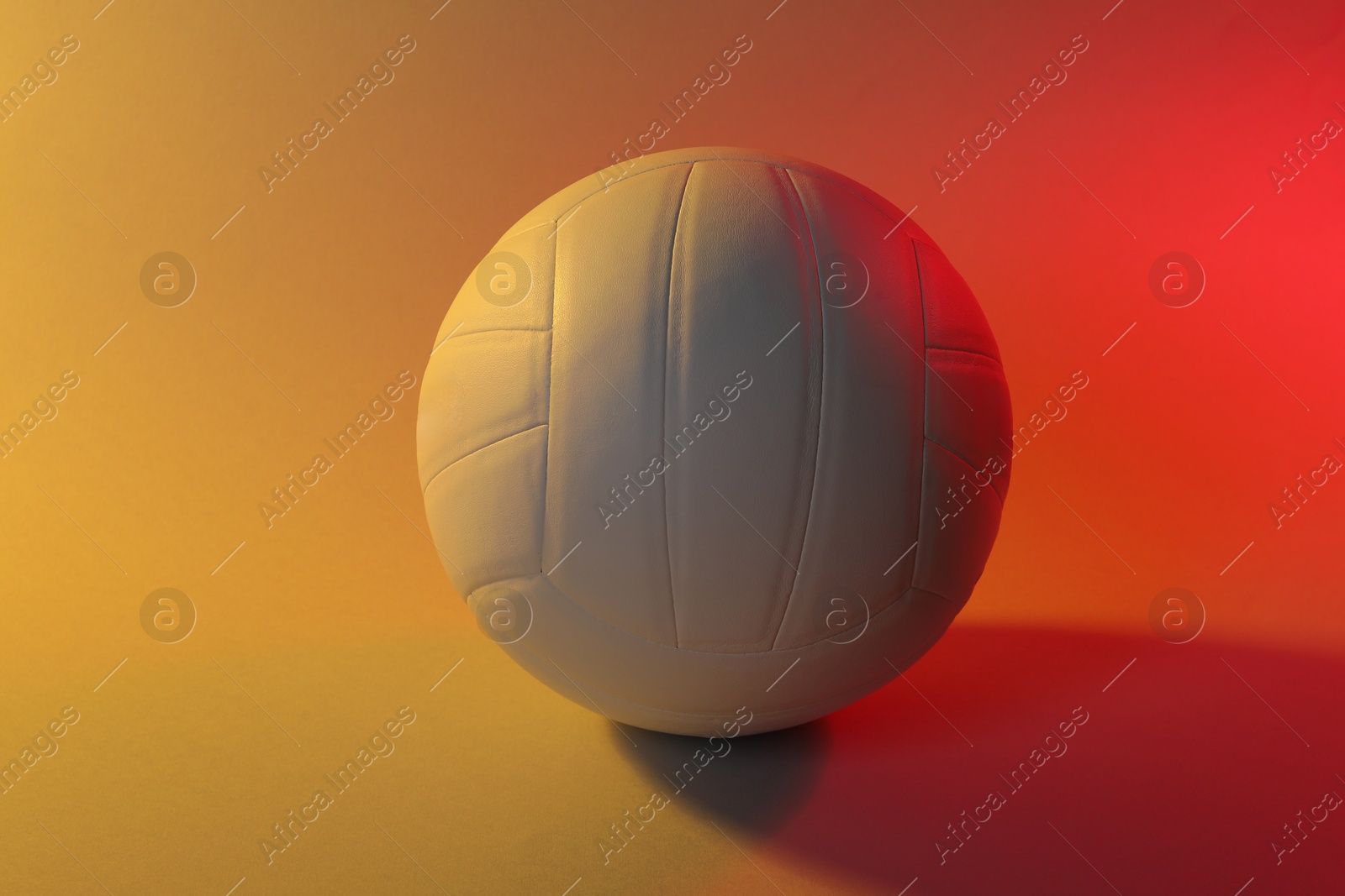 Photo of Volleyball ball on light background in color lights