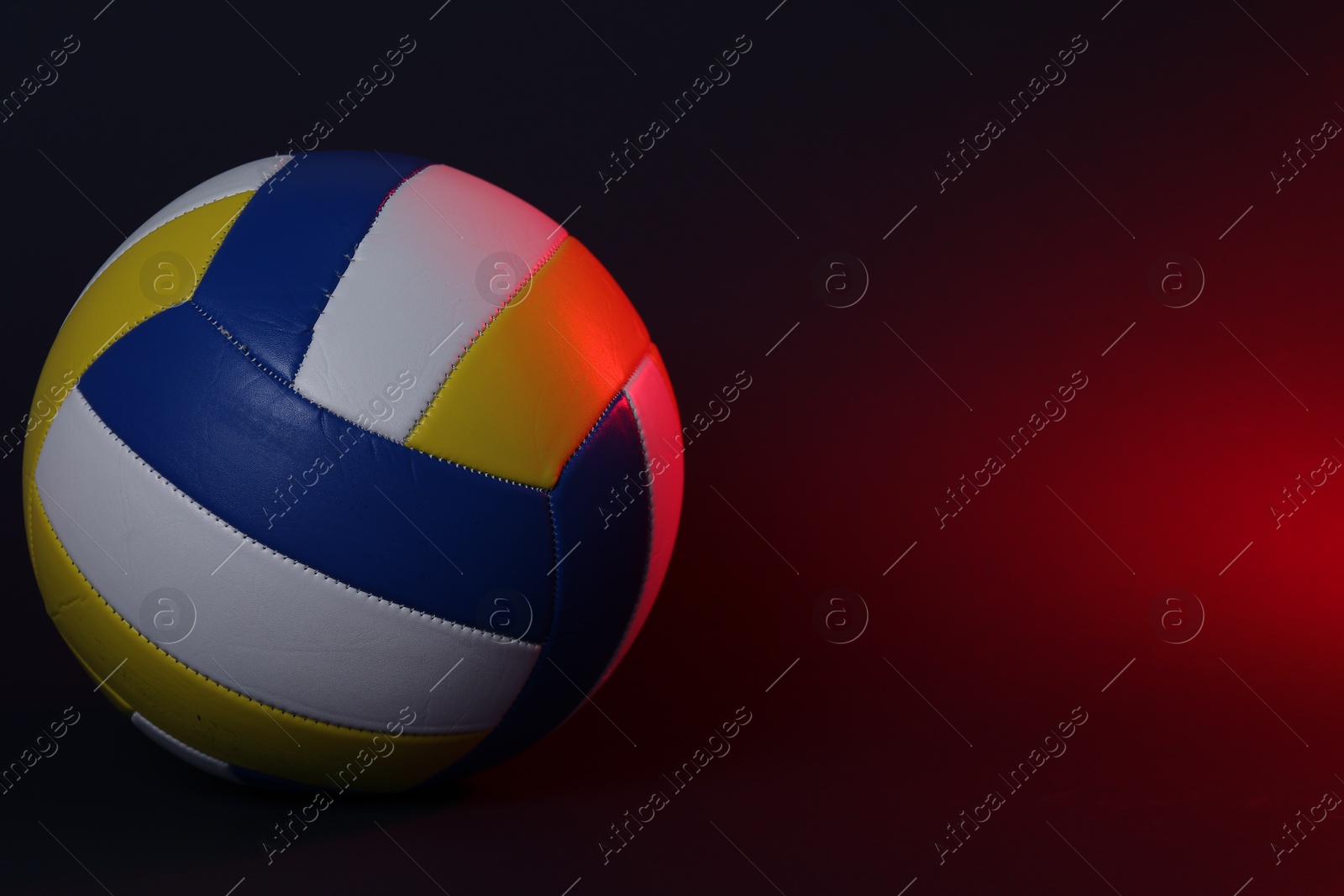 Photo of Volleyball ball on dark background in color light. Space for text