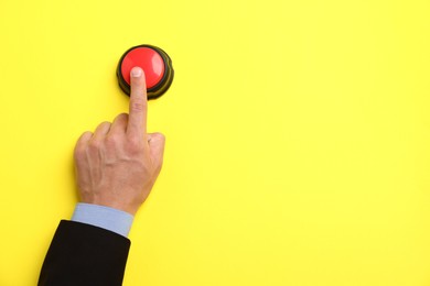 Photo of Man pressing button on yellow background, top view. Space for text