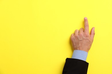 Photo of Man touching something on yellow background, top view. Space for text