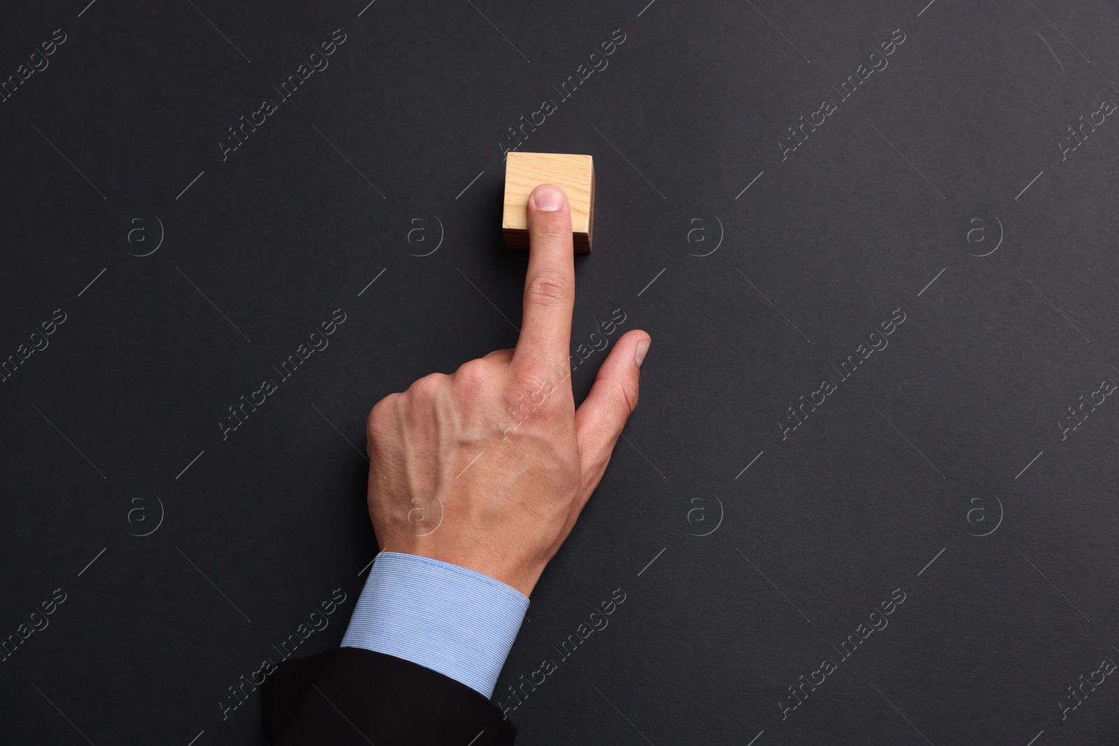 Man touching wooden cube on black background, top view Photo of Man touching wooden cube on black background, top view