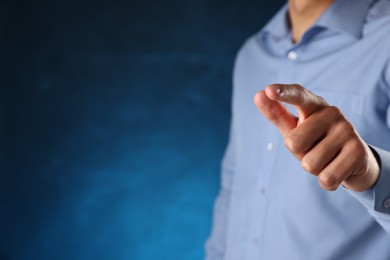 Photo of Man touching something on blue background, closeup. Space for text