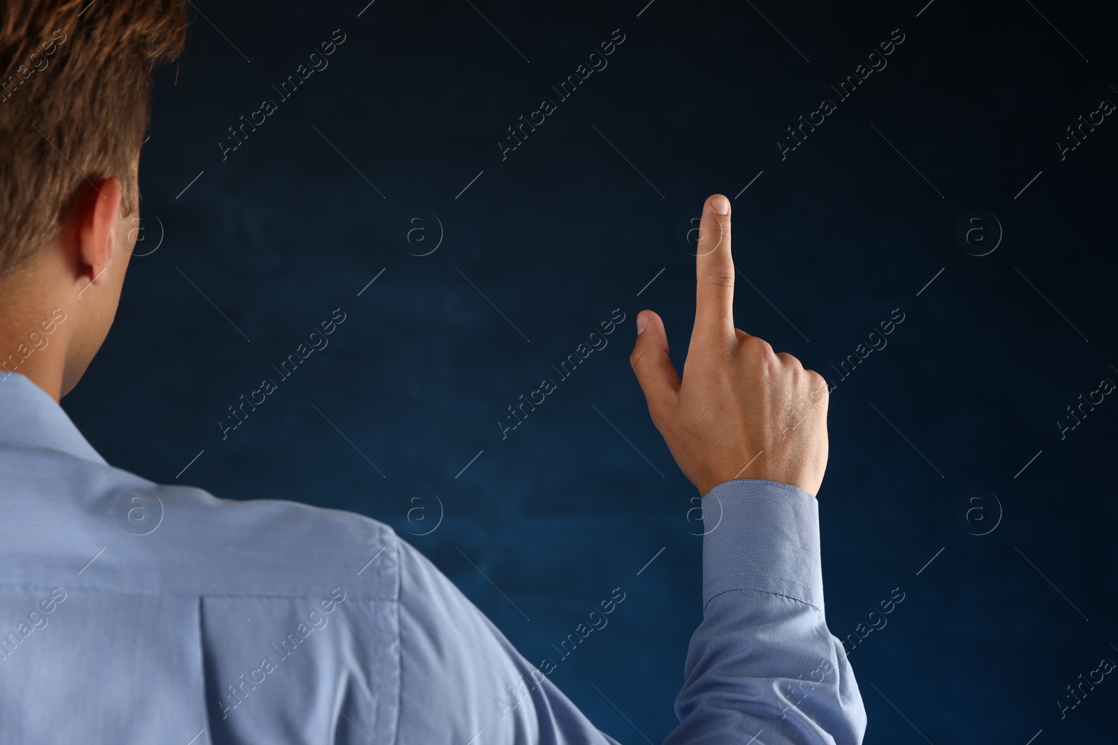 Photo of Man touching something on blue background, back view