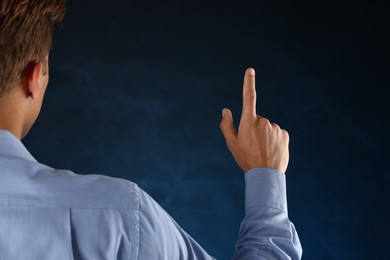 Photo of Man touching something on blue background, back view