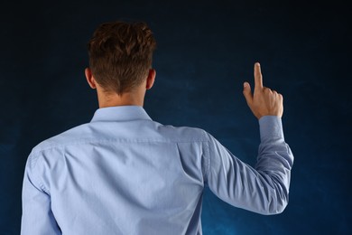 Photo of Man touching something on blue background, back view