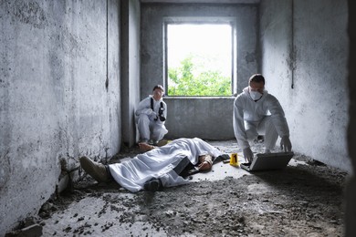 Photo of Forensic experts working at crime scene with dead man's body inside abandoned building