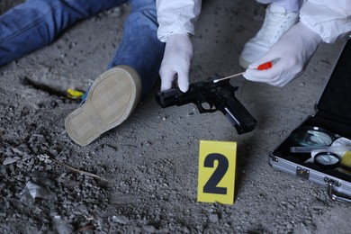 Photo of Forensic expert working at crime scene with dead body inside abandoned building, closeup