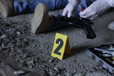Photo of Forensic expert working at crime scene with dead body inside abandoned building, closeup