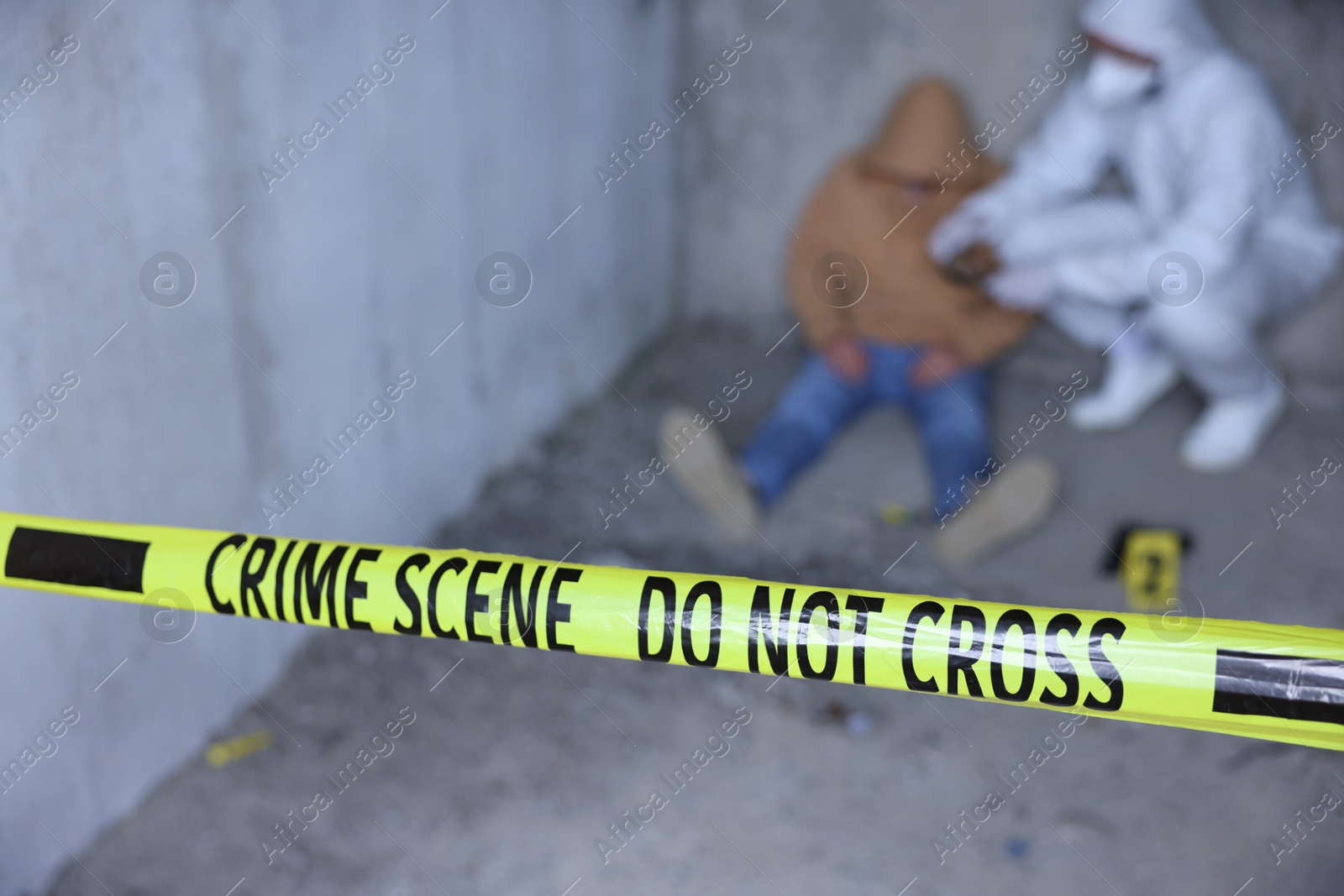 Photo of Forensic expert working at crime scene with dead body inside abandoned building, focus on yellow police tape